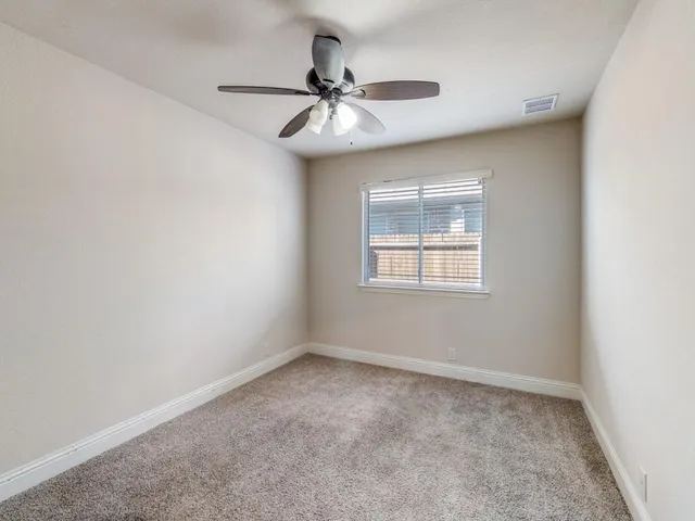 an empty room with a window and a fan