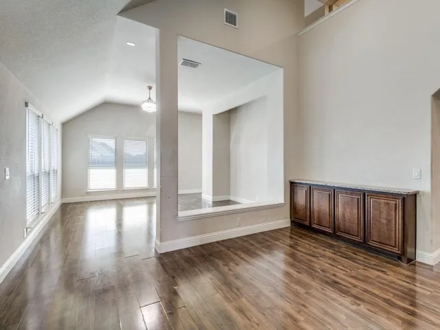 a view of an empty room with wooden floor and window