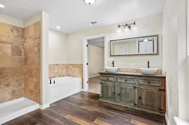 a spacious bathroom with a granite countertop sink a mirror and a bathtub