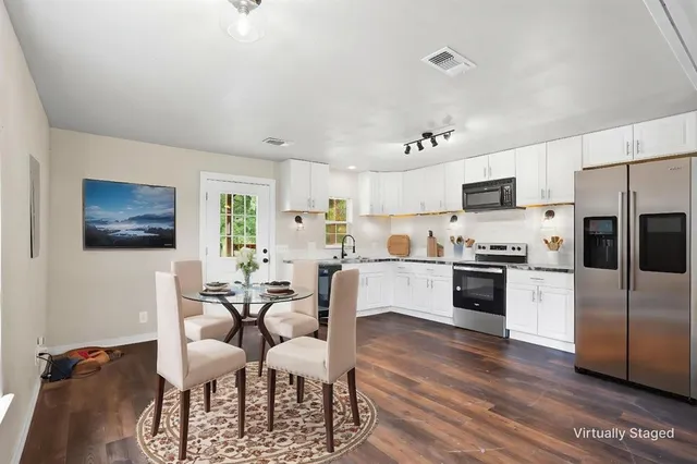 a kitchen with stainless steel appliances a dining table chairs microwave and sink