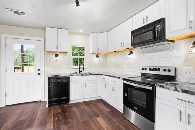 a kitchen with granite countertop a stove top oven and sink
