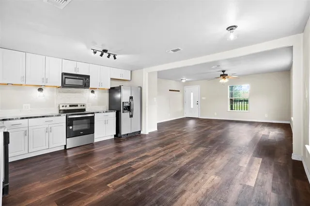 a kitchen with granite countertop a refrigerator and a stove top oven