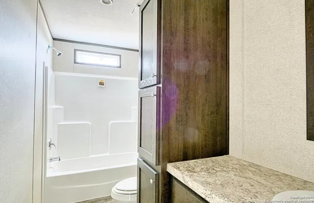 a bathroom with a granite countertop sink toilet and shower