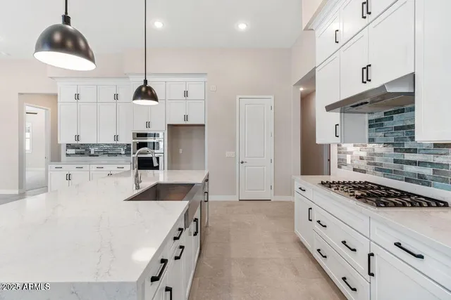 a kitchen with stainless steel appliances kitchen island granite countertop a sink a stove and a refrigerator