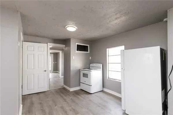 a view of a kitchen with a sink and dishwasher a refrigerator with white cabinets
