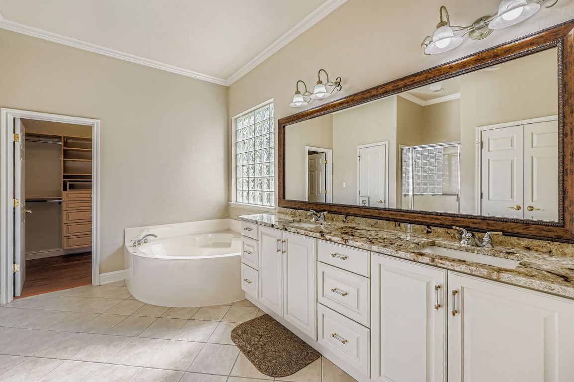 5000 Mission Oaks Boulevard, Unit 61 Austin, TX 78735 - Photo 15 of 27 Bathroom featuring crown molding, double vanity, tile patterned floors, a bath, and a shower stall