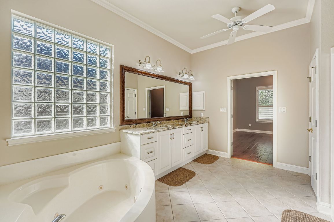 5000 Mission Oaks Boulevard, Unit 61 Austin, TX 78735 - Photo 16 of 27 Bathroom with tile patterned floors, ornamental molding, vanity, a jetted tub, and ceiling fan