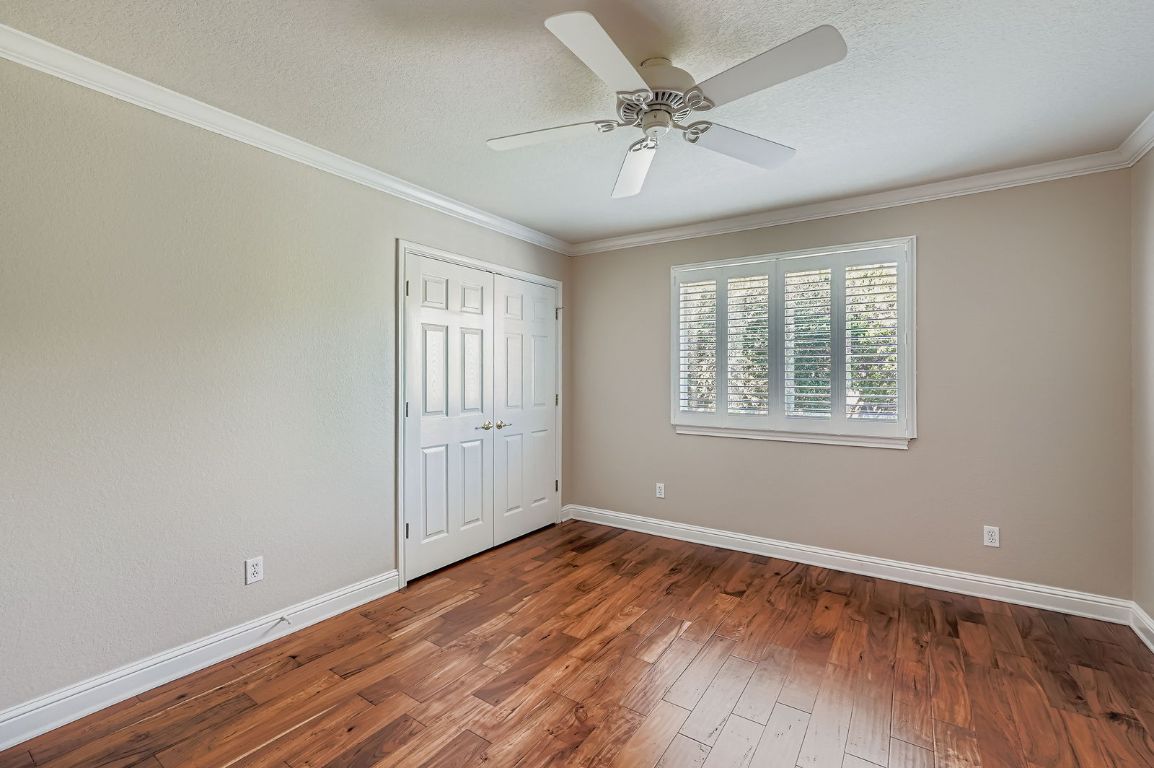 5000 Mission Oaks Boulevard, Unit 61 Austin, TX 78735 - Photo 19 of 27 Unfurnished bedroom featuring crown molding, wood-type flooring, a closet, a textured ceiling, and a ceiling fan