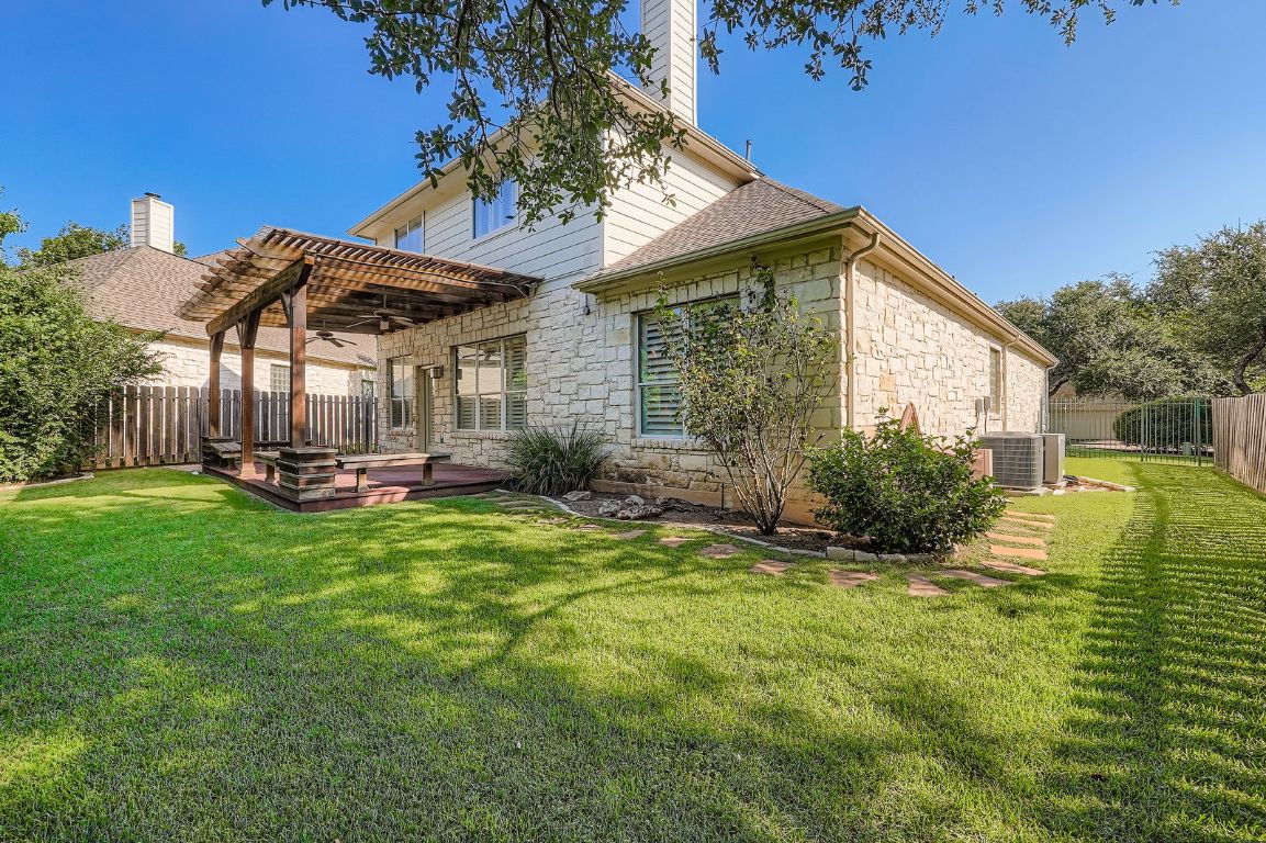 5000 Mission Oaks Boulevard, Unit 61 Austin, TX 78735 - Photo 26 of 27 Rear view of house featuring a fenced backyard, stone siding, a pergola, and a deck