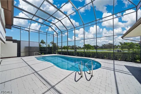 a swimming pool with lawn chairs and glass door