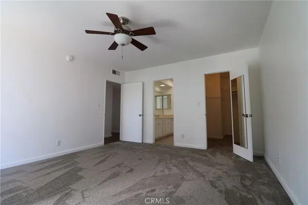 an empty room with closet and a ceiling fan