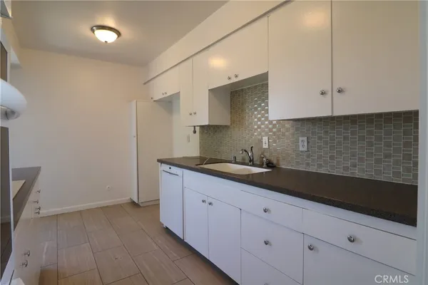a kitchen with granite countertop white cabinets and sink