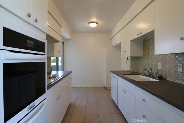 a kitchen with granite countertop stainless steel appliances a sink stove top oven and wooden floor
