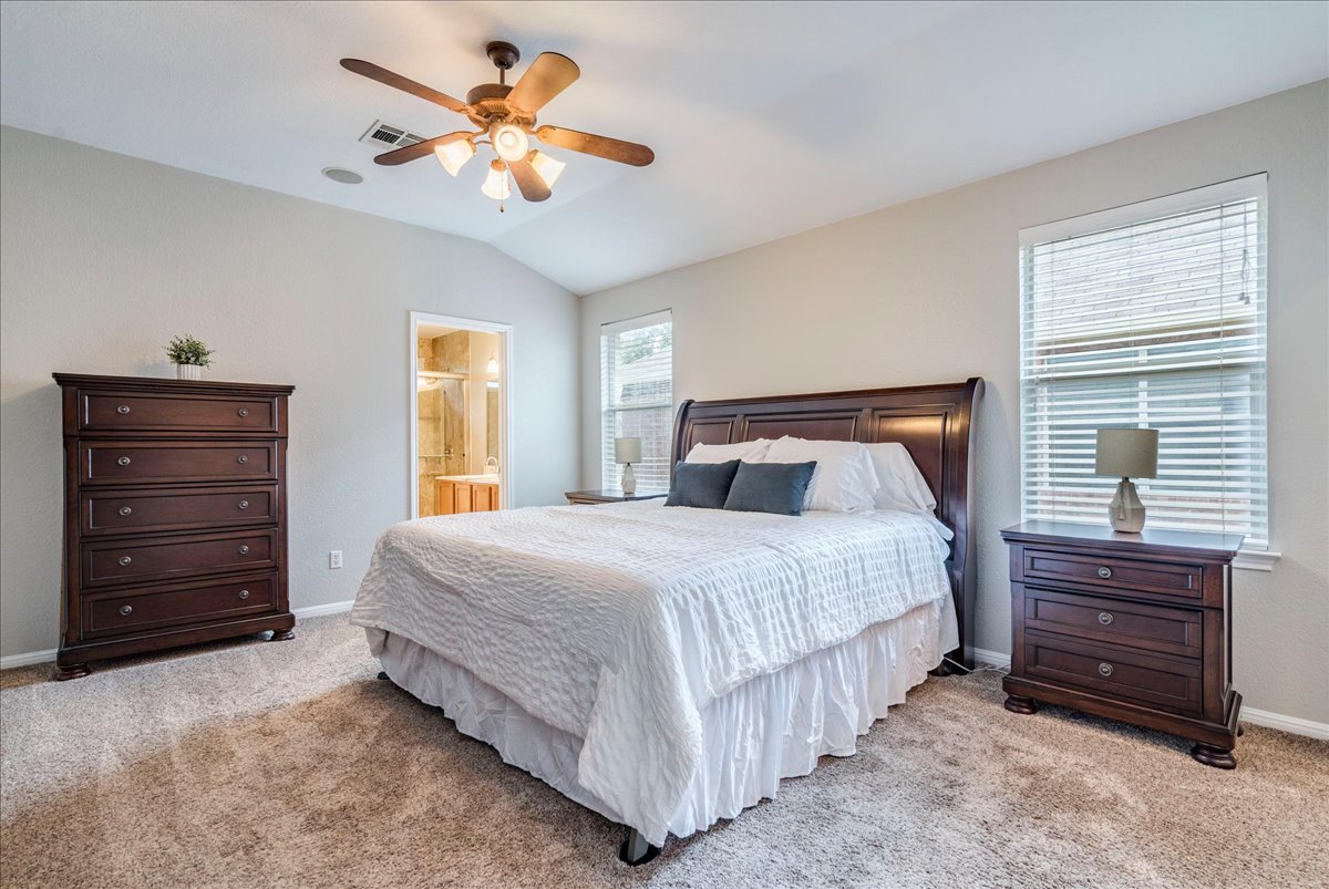 1151 Stone Rim Loop Buda, TX 78610 - Photo 15 of 36 Spacious primary bedroom with light carpeted flooring, ceiling fan,
