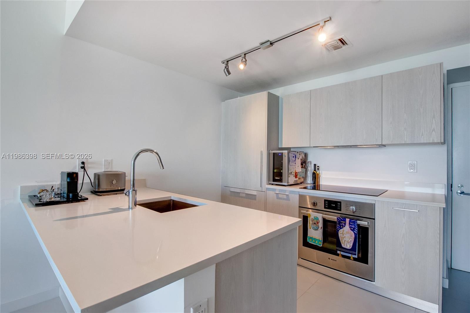 501 Northeast 31st Street, Unit 1502 Miami, FL 33137 - Photo 5 of 12 a kitchen with a sink a stove and cabinets