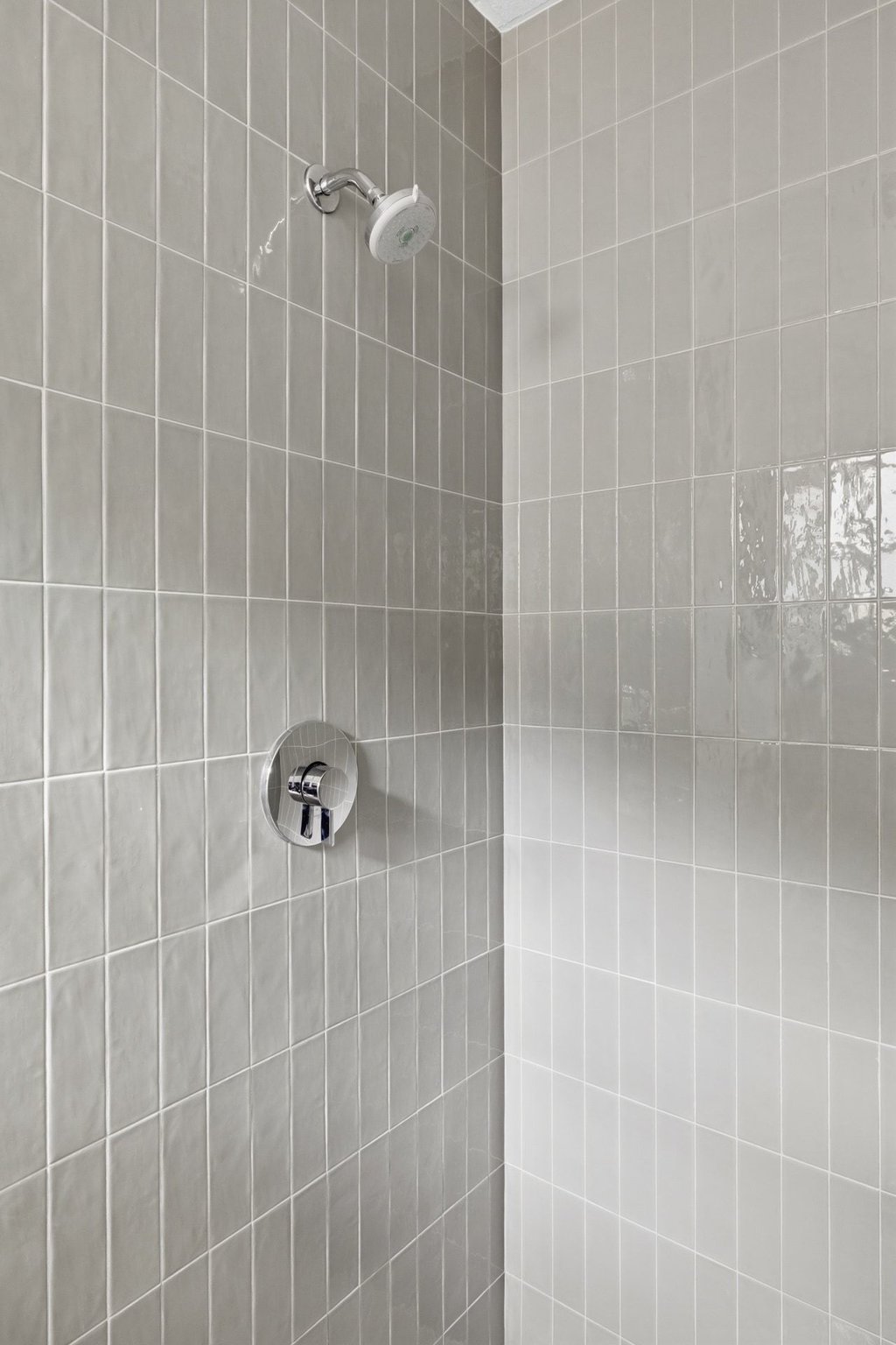 7507 Daugherty Street Austin, TX 78757 - Photo 16 of 25 Shower enclosure featuring vertical-stacked rectangular tile in a light gray finish, complemented by a chrome shower head and control valve