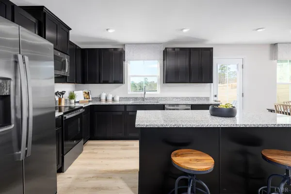a kitchen with stainless steel appliances granite countertop a sink counter space and chairs