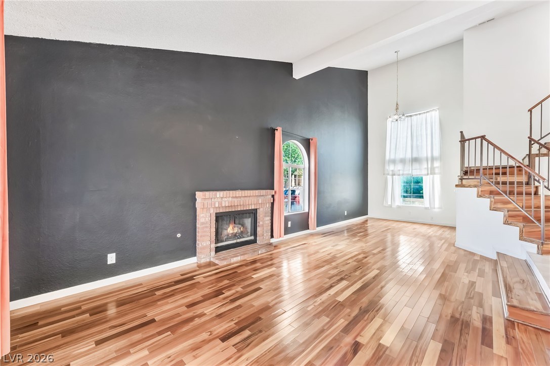 1402 Rim Fire Circle Henderson, NV 89014 - Photo 3 of 48 Gleaming wood floors and a classic brick fireplace anchor this soaring, open living space.