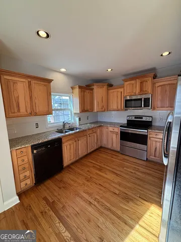 a large kitchen with wooden floors and stainless steel appliances