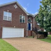 a front view of a house with a garden and trees