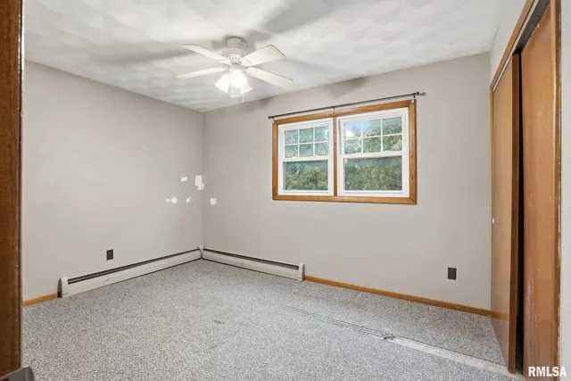 an empty room with windows and fan