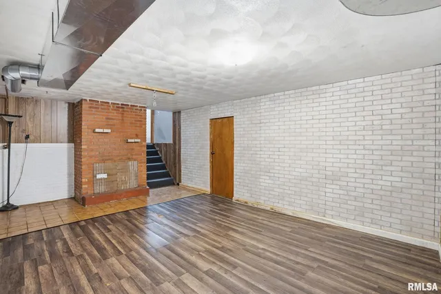 a view of an empty room with wooden floor and cabinets