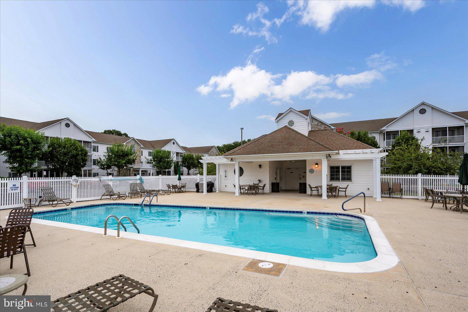 30611 Cedar Neck Road, Unit 2107 Ocean View, DE 19970 - Photo 40 of 44 a view of a house with a swimming pool and a chairs