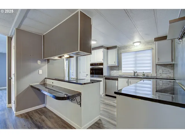 a kitchen with kitchen island granite countertop a sink cabinets and stainless steel appliances