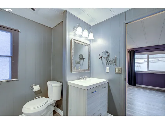 a bathroom with a sink vanity granite toilet and a mirror