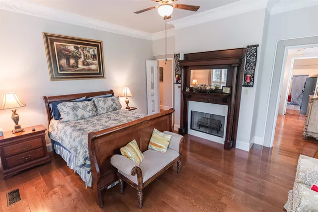 a bedroom with a bed wooden floor and a large window