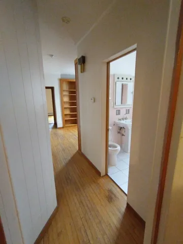 a view of a hallway with wooden floor and a bathroom