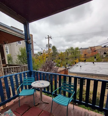 a balcony with wooden floor table and chairs