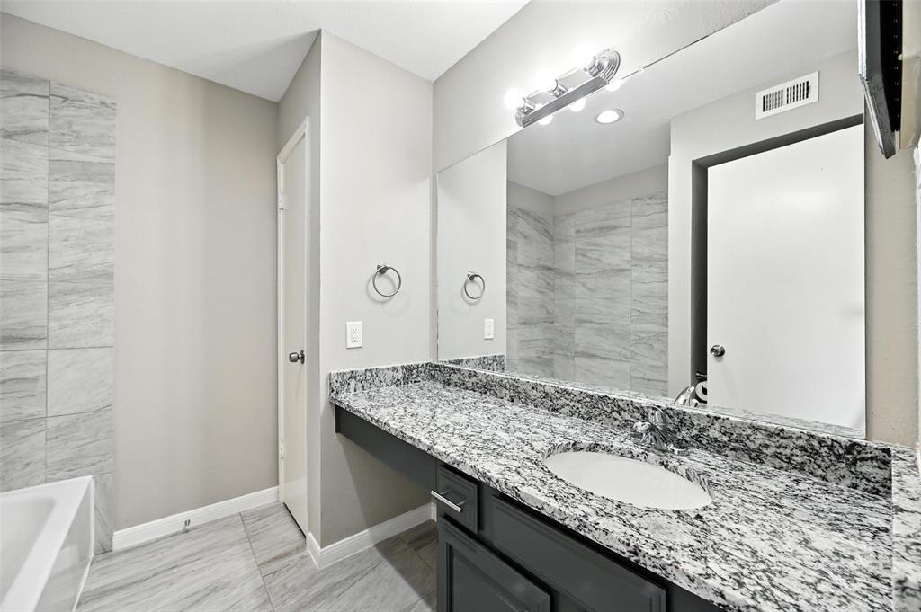 8545 Midpark Road, Unit 66 Dallas, TX 75240 - Photo 23 of 27 a bathroom with a granite countertop sink and a mirror