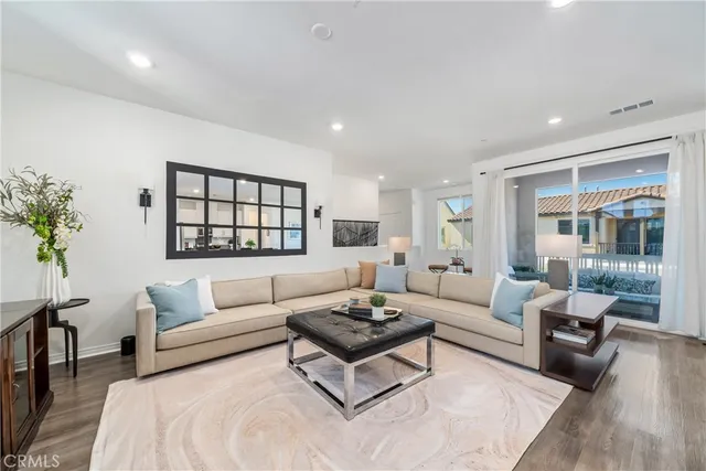 a kitchen with stainless steel appliances granite countertop a stove top oven a sink a dining table and chairs with wooden floor