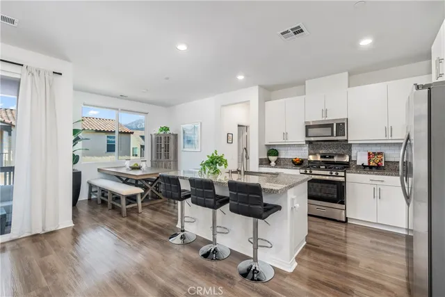 a kitchen with stainless steel appliances kitchen island granite countertop a sink refrigerator and cabinets