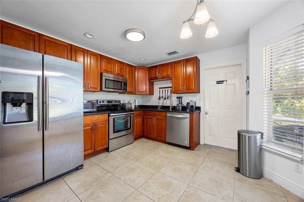 441 3rd Street Southwest Naples, FL 34117 - Photo 9 of 22 Kitchen featuring wood cabinetry, stainless steel appliances, dark countertops, and tile flooring