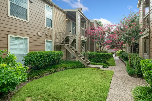 a view of a house with a yard and potted plants