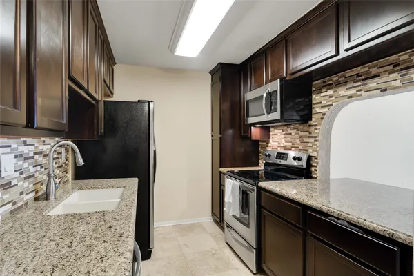 a kitchen with stainless steel appliances granite countertop a refrigerator a stove and a sink with wooden floor