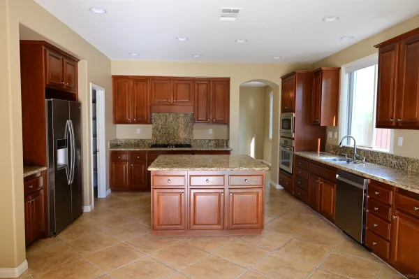 a kitchen with stainless steel appliances granite countertop a refrigerator a stove and a sink