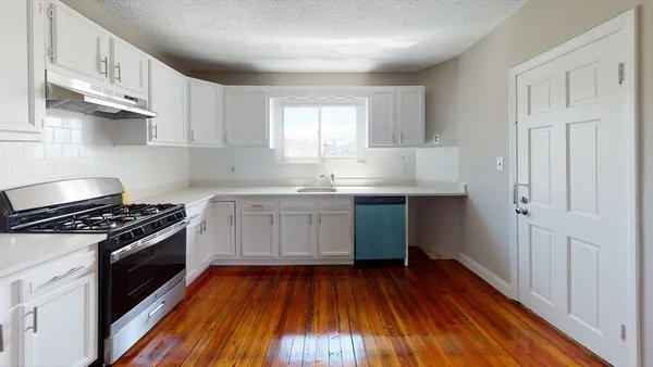 a kitchen with granite countertop wooden floors and white stainless steel appliances