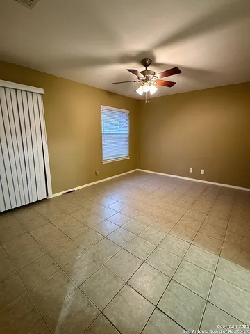 an empty room with windows and fan