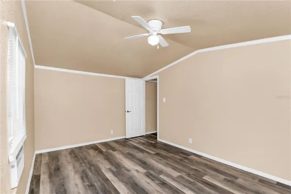 an empty room with a fan & a window