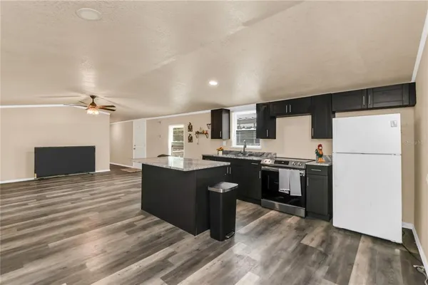 a kitchen with stainless steel appliances kitchen island granite countertop a refrigerator a sink dishwasher and a stove with wooden floor