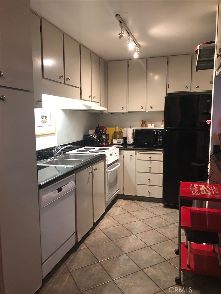 711 Pacific Coast Highway, Unit 303 Huntington Beach, CA 92648 - Photo 15 of 22 a kitchen with granite countertop a refrigerator and a sink