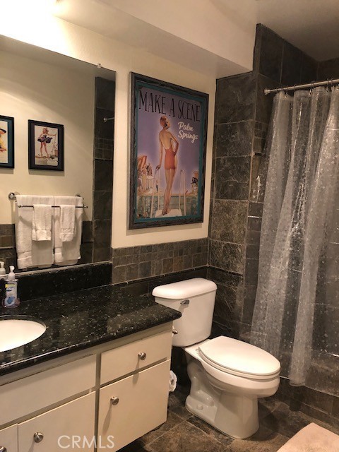 711 Pacific Coast Highway, Unit 303 Huntington Beach, CA 92648 - Photo 19 of 22 a bathroom with a granite countertop toilet a sink and a shower