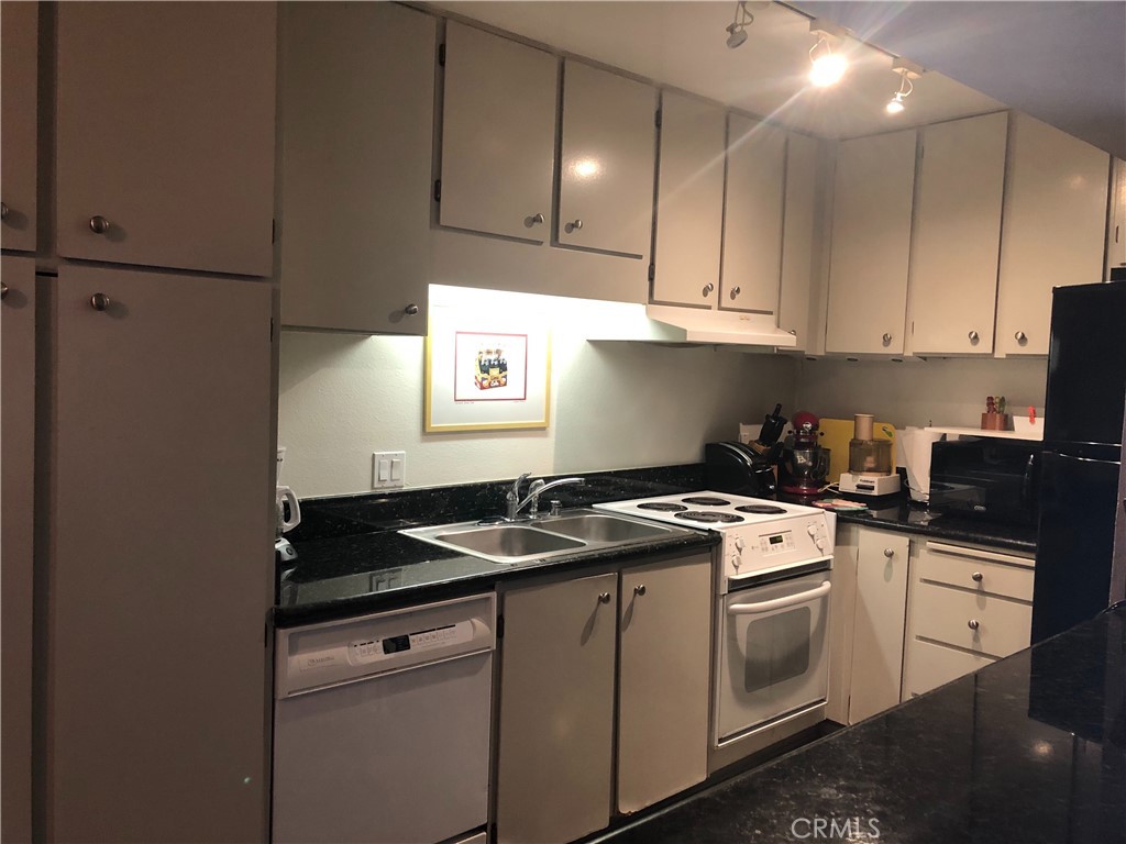 711 Pacific Coast Highway, Unit 303 Huntington Beach, CA 92648 - Photo 22 of 22 a kitchen with granite countertop cabinets and white appliances