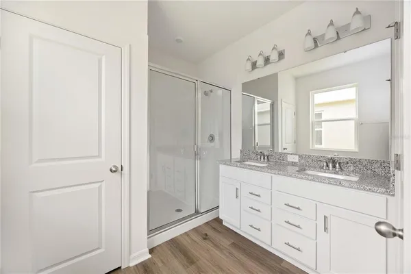 a bathroom with a double vanity sink and mirror with shower