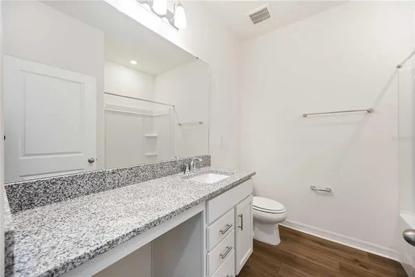a bathroom with a granite countertop sink a toilet and a mirror