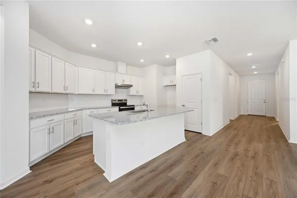 a kitchen with stainless steel appliances granite countertop a white stove top oven and white cabinets
