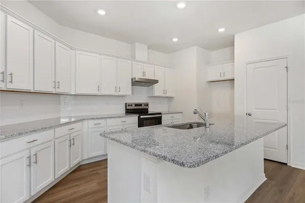 a kitchen with kitchen island granite countertop a sink a center island and cabinets